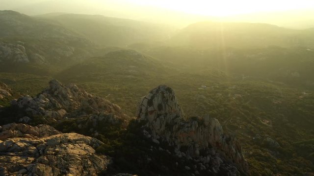 Video from above, aerial view oa a spectacular sunset behind some granite mountains in Sardinia, Italy.