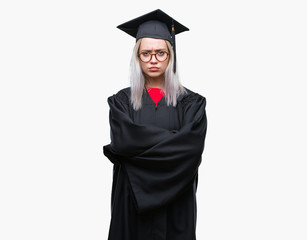 Young blonde woman wearing graduate uniform over isolated background skeptic and nervous, disapproving expression on face with crossed arms. Negative person.