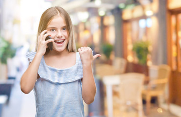 Fototapeta premium Young beautiful girl talking on the phone over isolated background pointing and showing with thumb up to the side with happy face smiling