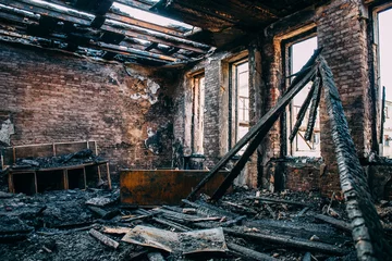 Gordijnen Burnt room interior with walls, furniture and floor in ash and coal, ruined building after fire © DedMityay
