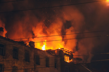 Night fire at roof in building, burning house with smoke, Fire disaster and accident tragedy