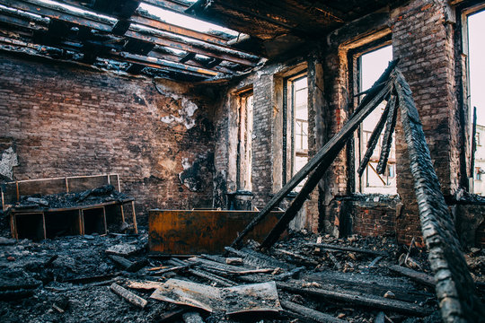 Burnt room interior with walls, furniture and floor in ash and coal, ruined building after fire