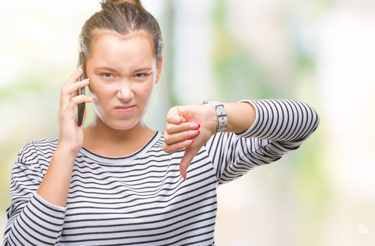 Young beautiful caucasian woman talking on smartphone over isolated background with angry face, negative sign showing dislike with thumbs down, rejection concept