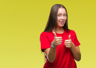 Young beautiful caucasian woman over isolated background doing happy thumbs up gesture with hand. Approving expression looking at the camera with showing success.