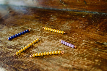 Beads to learn to count in a montessori classroom on aged wood.