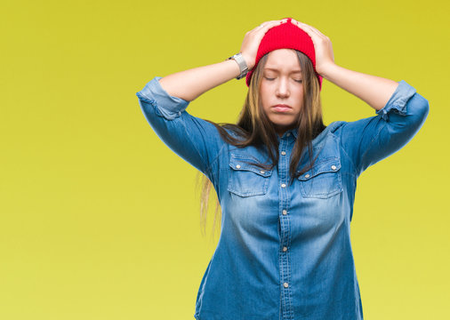 Young caucasian beautiful woman wearing wool cap over isolated background suffering from headache desperate and stressed because pain and migraine. Hands on head.