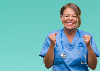 Middle age senior nurse doctor woman over isolated background excited for success with arms raised celebrating victory smiling. Winner concept.