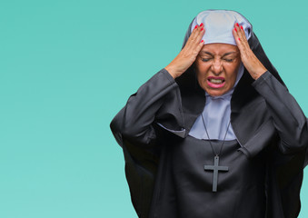 Middle age senior christian catholic nun woman over isolated background suffering from headache desperate and stressed because pain and migraine. Hands on head.
