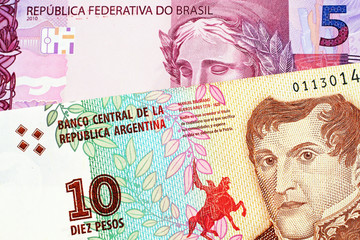 A macro image of a pink Brazilian five reais note with an Argentinian ten peso bill