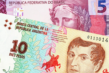 A macro image of a pink Brazilian five reais note with an Argentinian ten peso bill