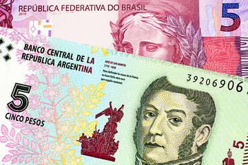 A macro image of a pink Brazilian five reais note with an Argentinian five peso bill