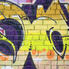 Fragment of graffiti drawings. The old wall decorated with paint stains in the style of street art culture. Colored background texture in warm tones