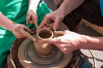 Pottery training, four hands make a pot of clay