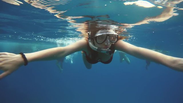 Woman dive underwater in snorkeling diving mask and snorkel in the clear blue sea water.