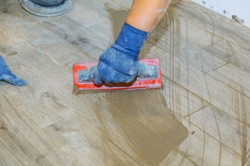 Hand of flooring on gray color of new grout tile on tile gray for the final step for flooring