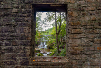 Historic stone mill window framing waterfall