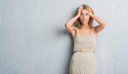 Beautiful young woman standing over grunge grey wall stressed with hand on head, shocked with shame and surprise face, angry and frustrated. Fear and upset for mistake.