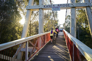 Kanes Bridge, a pedestrian single-span suspension bridge, over the Yarra River with family crossing it, at Yarra Bend Park, Melbourne, Victoria, Australia
