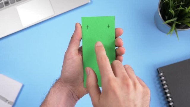 Green screen smartphone being used over a working office desk. Chroma key square screen.