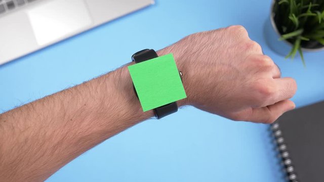 Smartwatch with green screen being used over a working office desk. Chroma key square screen.