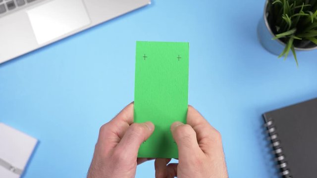 Green screen smartphone being used over a working office desk. Chroma key square screen.