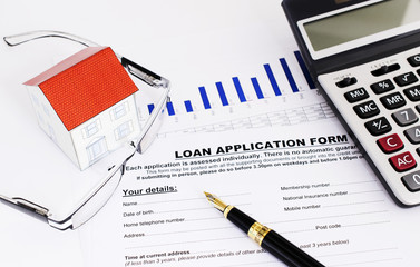 Mortgage loans concept with fountain pen and eyeglasses and paper house and calculator and loan application form documents