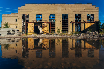 Abandoned industrial building reflected in pool of rainwater