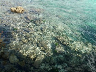 Naklejka na ściany i meble Rocks and corals are visible through the crystal clear waters