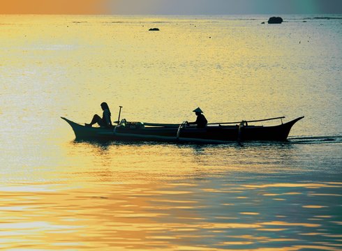 Silhouette of woman and boat man in boat at sunrise