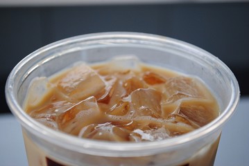 Top view of iced coffee with ice cubes, in plastic glass