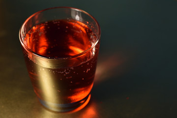 Glass of cherry soda drink on golden surface