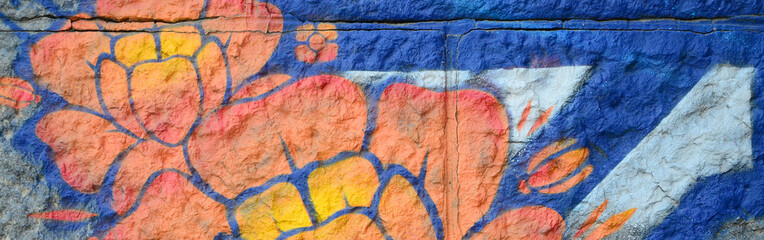 Fragment of graffiti drawings. The old wall decorated with paint stains in the style of street art culture. Orange flower