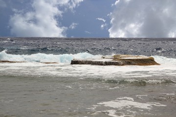 A rocky platform stands out dividing the shorelines and the huge waves of the deep blue Pacific Ocean