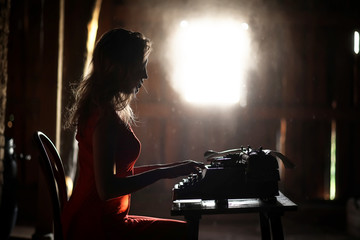 Fototapeta na wymiar A girl in retro style prints on an old typewriter
