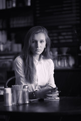 A girl in a cafe is drinking coffee. A woman is having breakfast