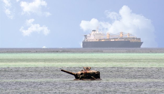Wreck of a Japanese world war 11 tanker submerged in the sea, Saipan The upper part of a submerged tanker protrudes off Susupe Beach in Saipan, with a big ship in the distance.