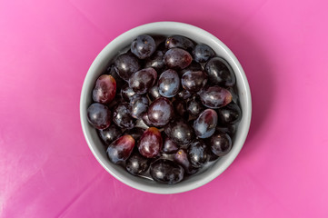 Red grapes in a bowl over a pink table