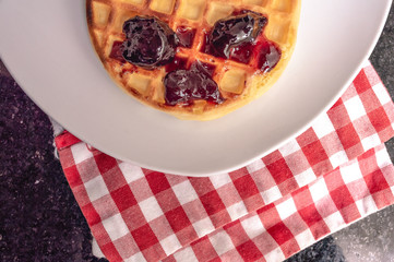 Waffle over a checkered napkin over a table. Top view closeup