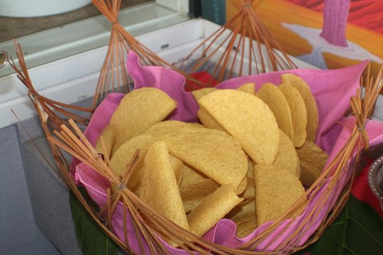 Crispy chips served in a wicker basket with pink cloth 