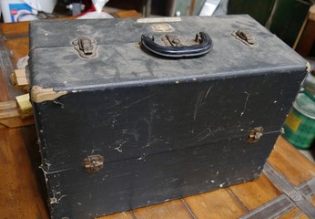 Battered and dusty black wooden chest with rusty knobs and locks