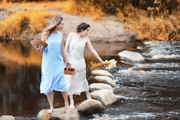 Girls in dresses in autumn on the river