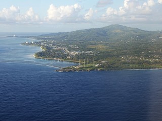 Fototapeta na wymiar Aerial view of Saipan western coast from a distance, with the deep blue waters of the Saipan-Tinian channel in between