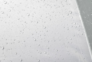 Water drops on waterproof fabric background. Raindrops on white umbrella.