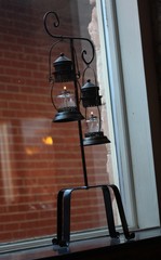 Oil lamps hanging from a steel rack by a windowpane