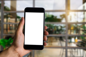 Hand holding white mobile phone with blank white screen  at the corner of the gym.