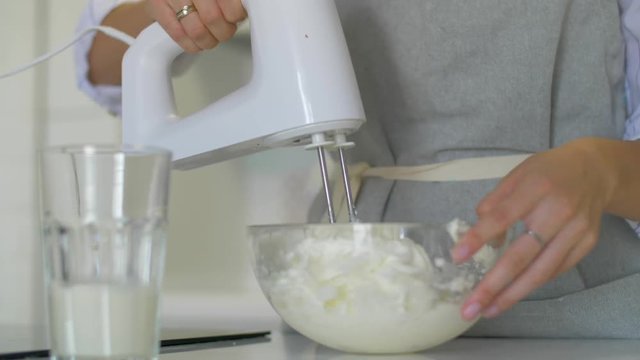 The process of making cream for a cake. Pastry Chef is beating the butter with a blender machine