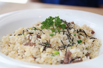 Oriental fried rice with corned beef, topped with green herbs 