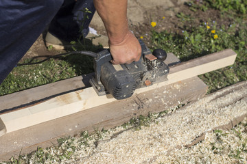 The carpenter works with an electric planer on a wooden Board