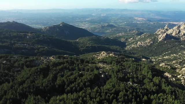 Video from above, aerial view of a beautiful valley surrounded by granite mountains and green vegetation, Monte Limbara, Sardinia, Italy.