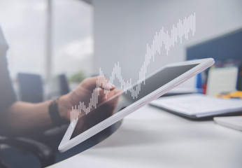 Naklejka premium Business man is holding the tablet, double exposure of candlestick chart for finance and trading